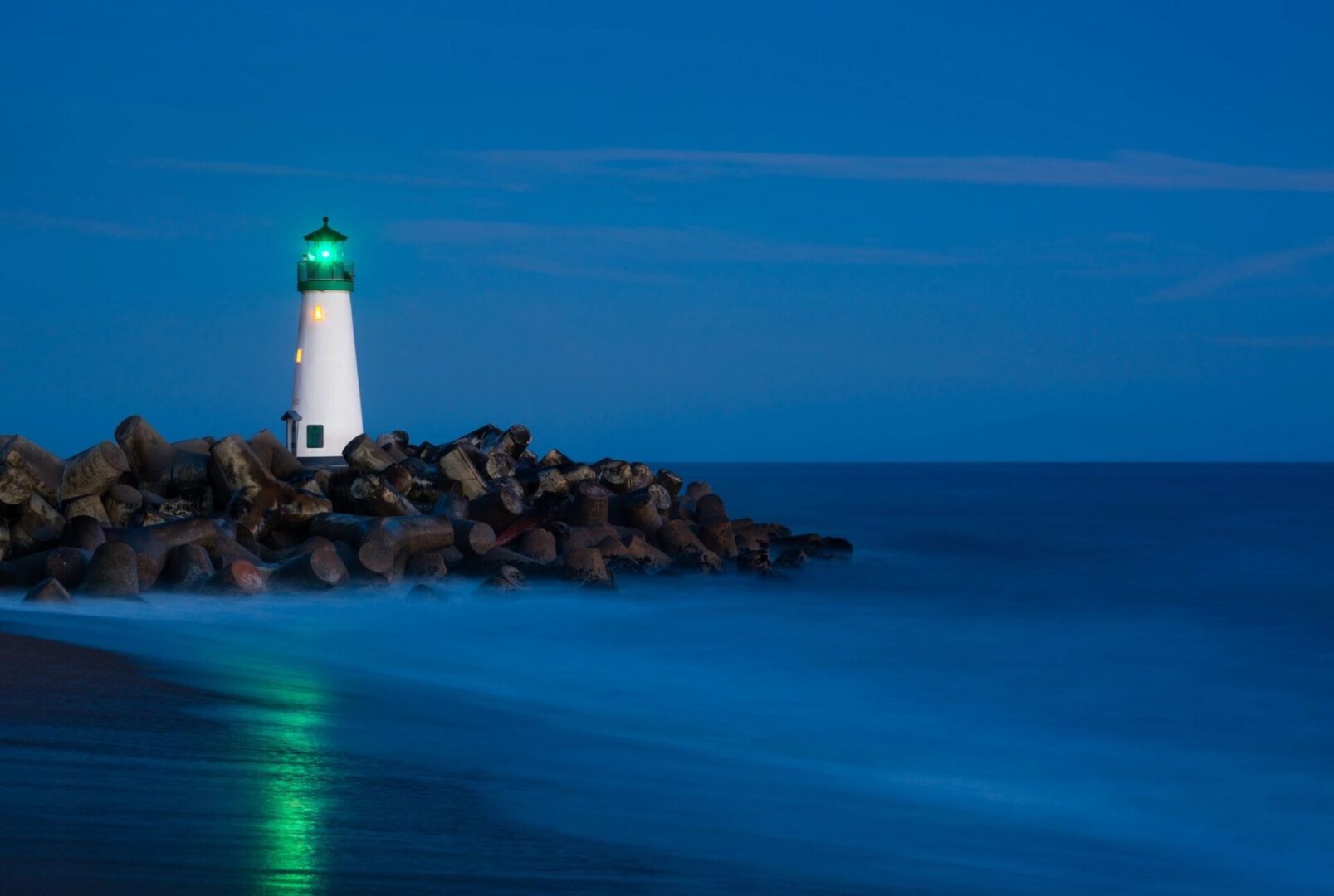 A lighthouse on the beach at night.