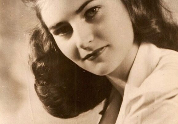 A young woman with long hair and a white shirt.