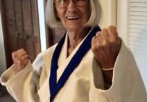 A woman in white shirt and red pants holding up her hands.