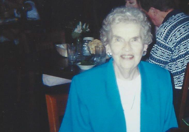 A woman in blue jacket standing next to table.