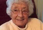 A woman with white hair sitting in a chair.