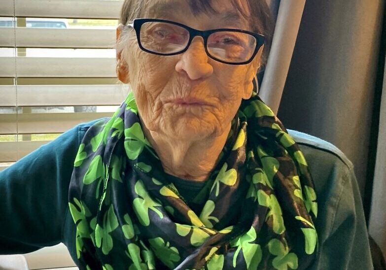 A woman wearing glasses and a green scarf.