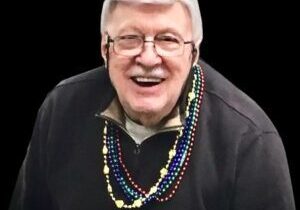 A man with glasses and beads around his neck.