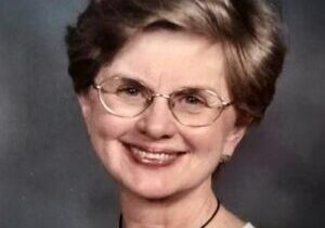 A woman with short hair wearing glasses and smiling.