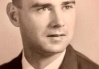 A man in suit and tie with short hair.