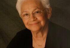 A woman with white hair and wearing glasses.