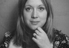 A black and white photo of a woman with her hand under the chin.