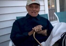 A man sitting on the porch holding a snake.