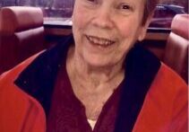 A woman sitting in a booth smiling for the camera.