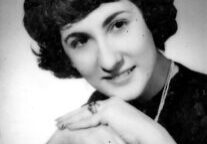 A black and white photo of a woman with her hands crossed.