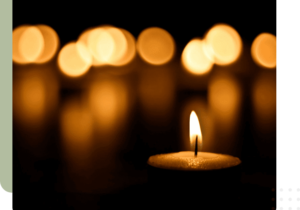 A candle is lit in front of some blurry lights.