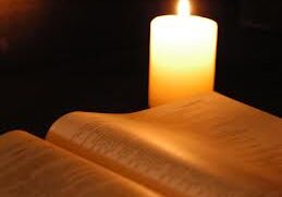 A candle is lit on top of an open bible.