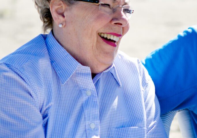 A woman sitting on the ground with her hands in her pockets.