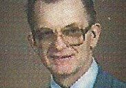 A man in glasses and suit jacket with tie.