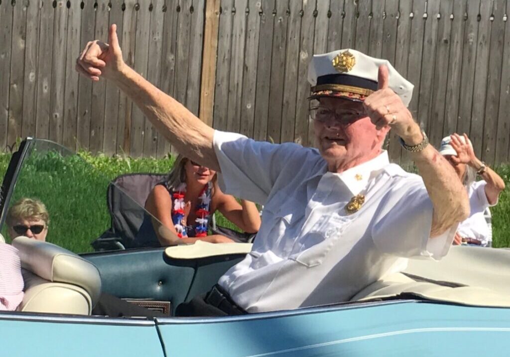 A man in a car with his hands raised.