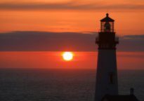 A lighthouse with the sun setting in the background.