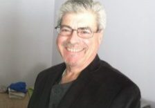 A man with grey hair and glasses smiling.