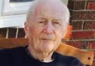 An older man sitting in a chair outside.