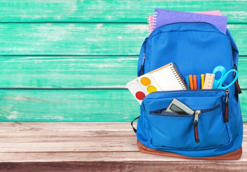 A blue backpack with school supplies in it.