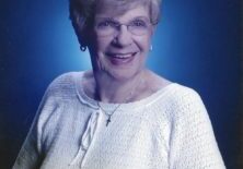 A woman in white shirt and glasses smiling.